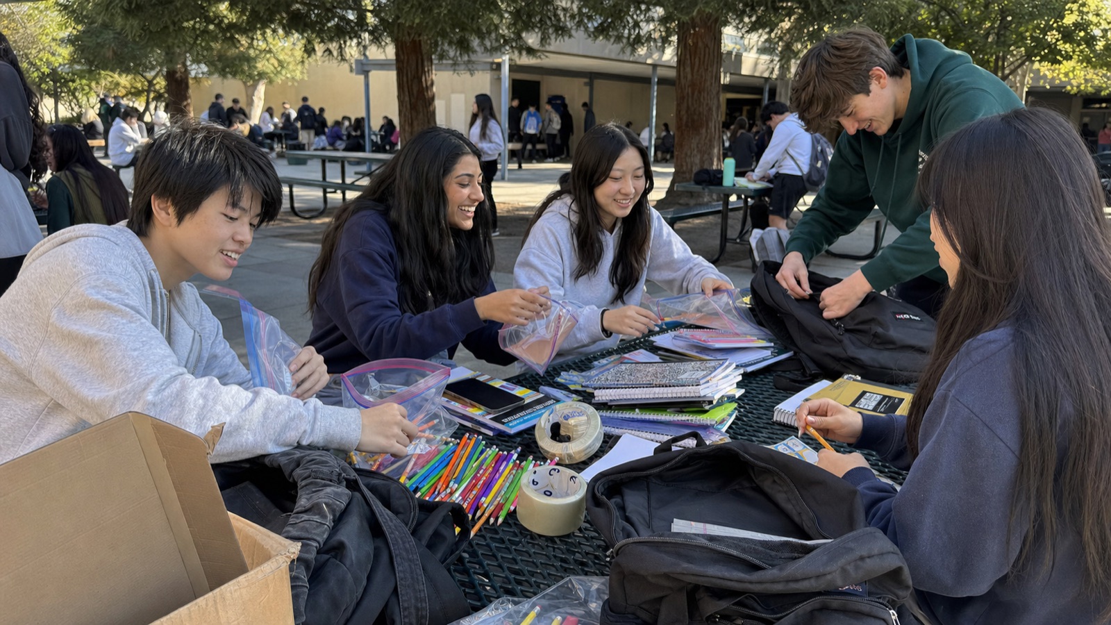 Students assembling school supply kits outdoors